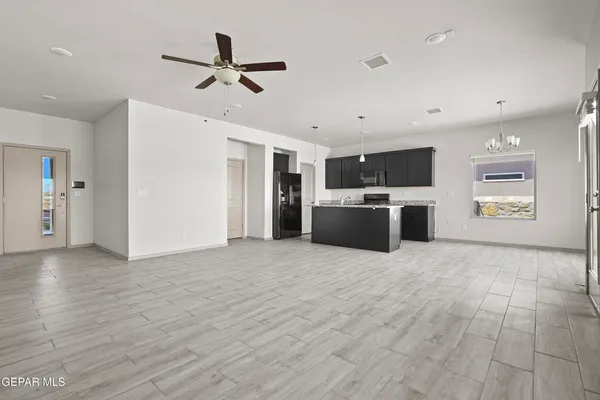 a living room with stainless steel appliances kitchen island granite countertop a refrigerator and a stove top oven