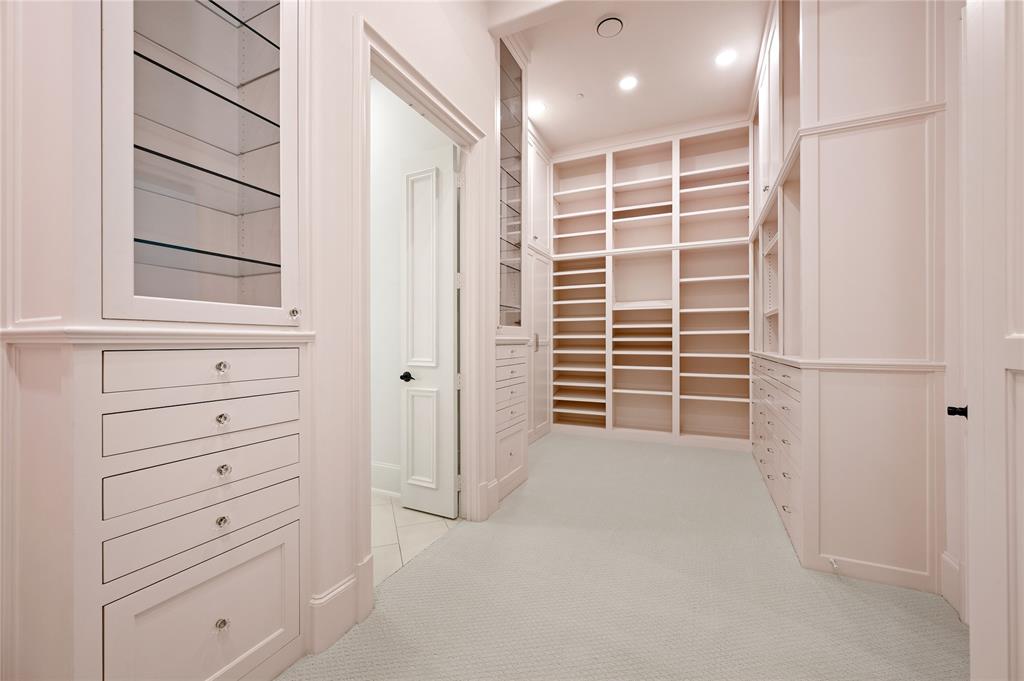 6900 Rockingham Court Colleyville, TX 76034 - Photo 15 of 40 Primary Closet left view with extensive custom built-in cabinetry, including glass-front upper cabinets, multiple drawers with crystal knobs, open shelving, and recessed lighting