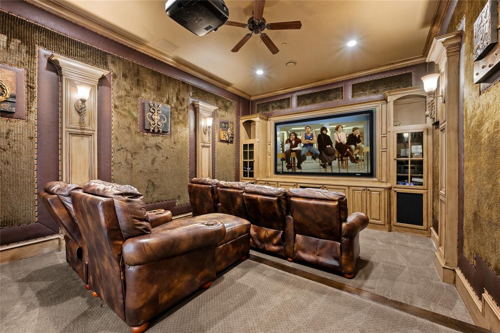 6900 Rockingham Court Colleyville, TX 76034 - Photo 23 of 40 Dedicated media room featuring a large projection screen, built-in cabinetry with integrated shelving, and recessed lighting