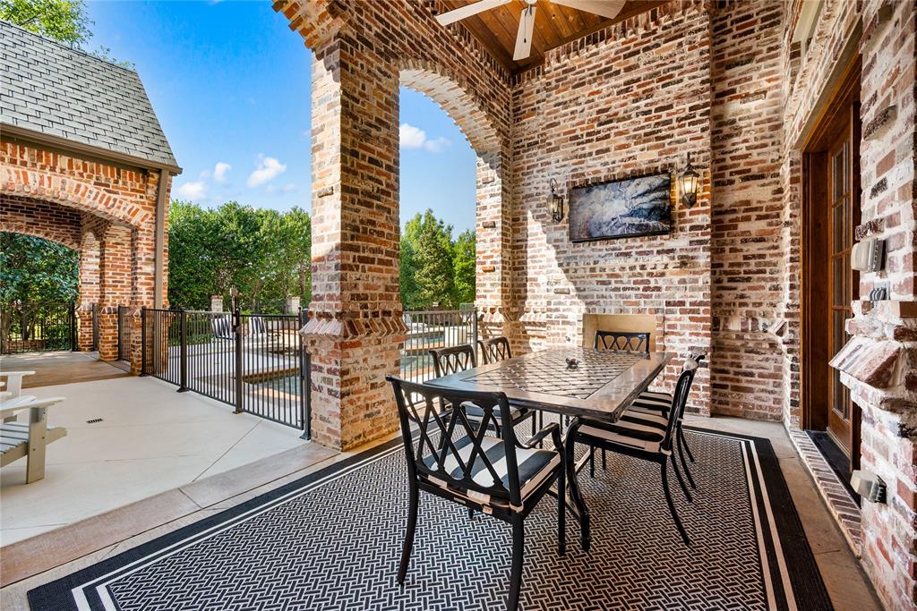 6900 Rockingham Court Colleyville, TX 76034 - Photo 33 of 40 Covered patio off of Formal Living Room features brick archways, a television, and a wood-paneled ceiling with a ceiling fan