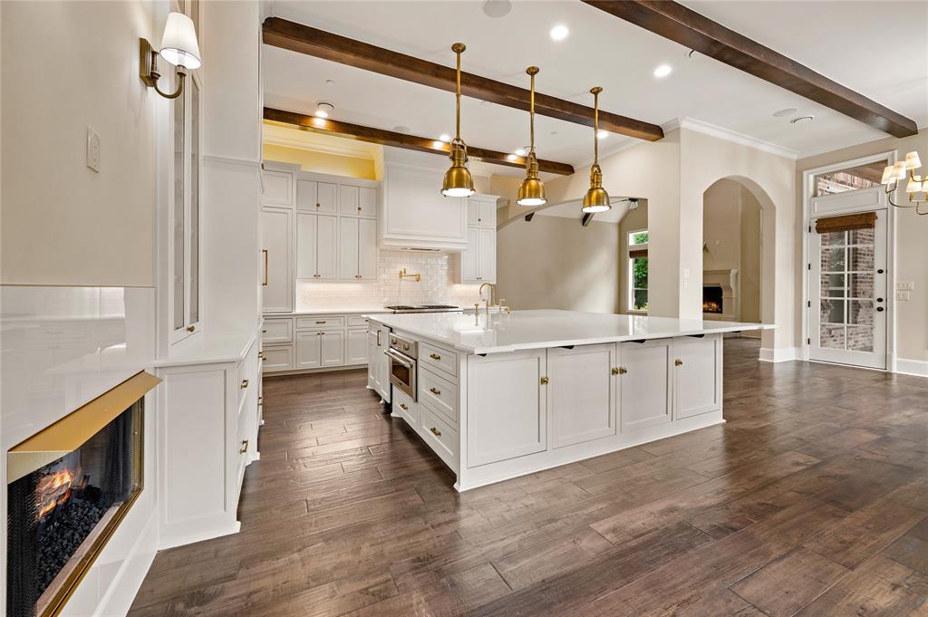 6900 Rockingham Court Colleyville, TX 76034 - Photo 9 of 40 Expansive kitchen featuring a large central island with white cabinetry and an integrated microwave, white shaker-style cabinetry, and wood-finish flooring
