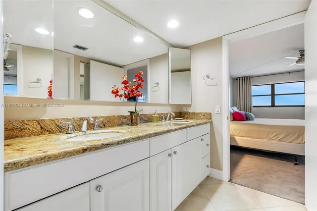 a en suite bathroom with a granite countertop sink and a large mirror