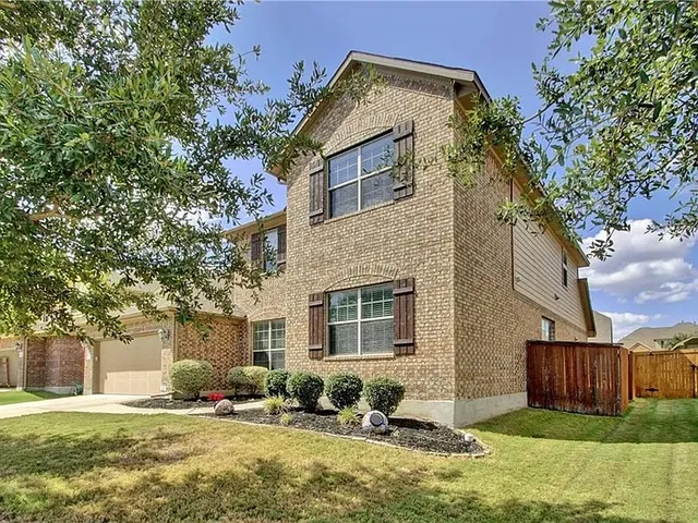 a front view of house with yard and trees in the background