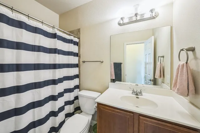 a bathroom with a sink a toilet a mirror and shower