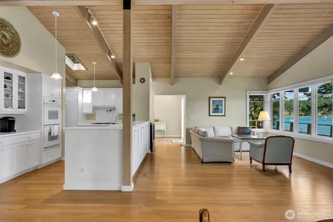 a living room with couches and kitchen view with wooden floor