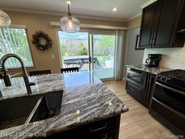 1115 Torpey Road Troy, MI 48083 - Photo 12 of 38 Kitchen with light stone counters, black appliances, light wood-style floors, crown molding, and decorative backsplash