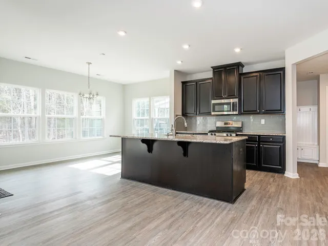 a kitchen with kitchen island granite countertop a stove top oven a sink and a counter space