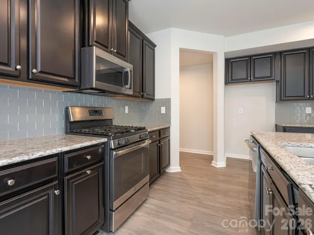 a kitchen with stainless steel appliances granite countertop a stove microwave and refrigerator