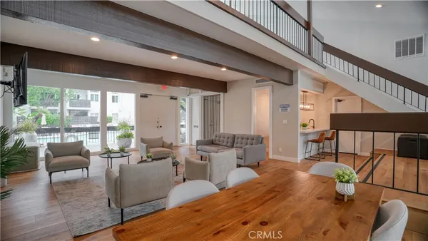 a living room with furniture large windows and wooden floor