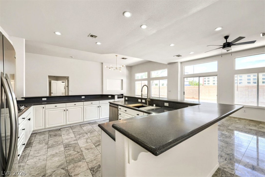 340 Kenya Road Las Vegas, NV 89119 - Photo 6 of 17 Polished tile flooring complements dark stone countertops and clean white cabinetry in this open kitchen.