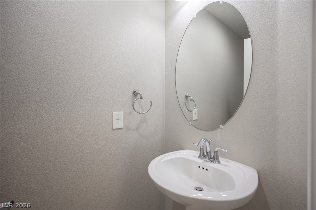 9916 Sable Point Street Las Vegas, NV 89178 - Photo 43 of 73 A pristine pedestal sink with a gleaming oval mirror offers a tidy and functional space.