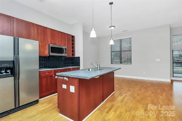 a kitchen with stainless steel appliances granite countertop a sink a refrigerator and a stove