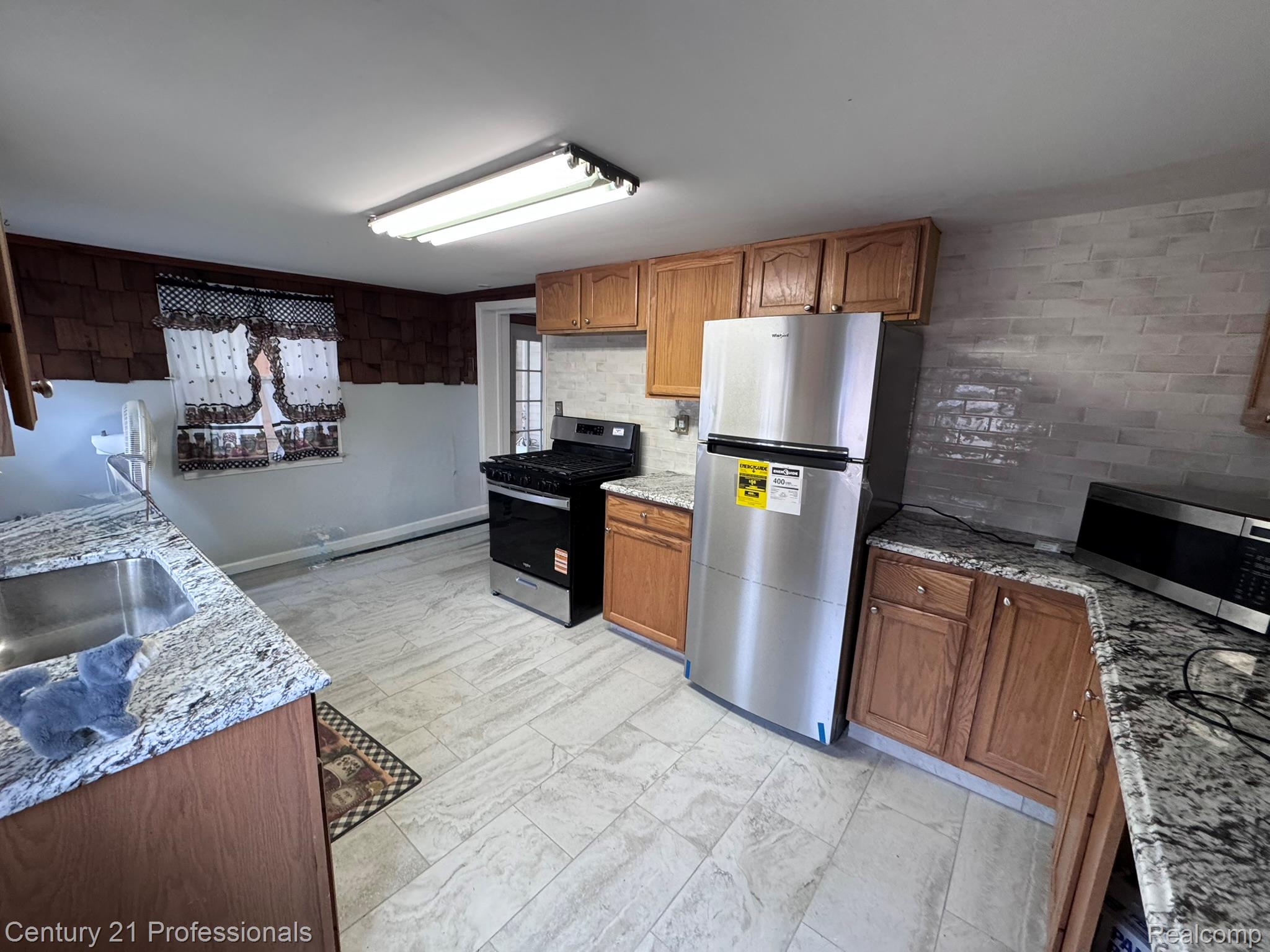 2021 West Rose Center Road Holly, MI 48442 - Photo 19 of 30 Kitchen featuring stainless steel appliances, wood finish cabinets, and light stone counters