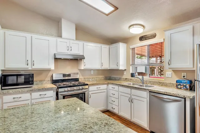 a kitchen with granite countertop a sink stainless steel appliances and cabinets