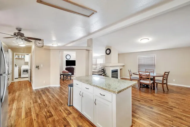 a open kitchen with granite countertop a sink appliances dining table and chairs