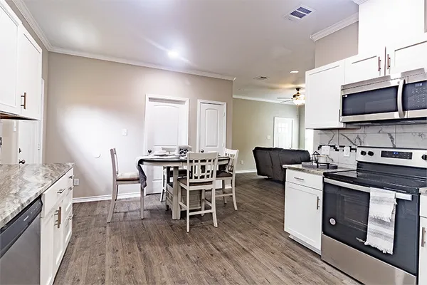 a open kitchen with stainless steel appliances granite countertop a stove top oven a sink dishwasher a dining table and chairs with wooden floor