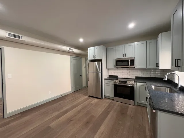 a kitchen with stainless steel appliances granite countertop a refrigerator sink and stove