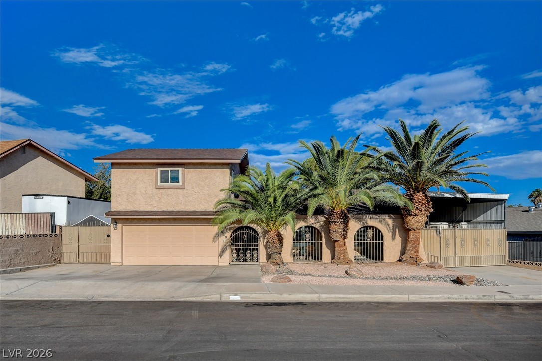 Mature palm trees and unique arched iron gates frame the front facade of this home.