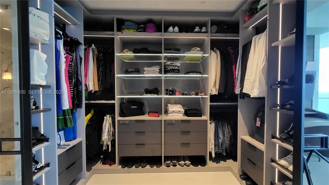 a view of walk in closet with clothes and shoes