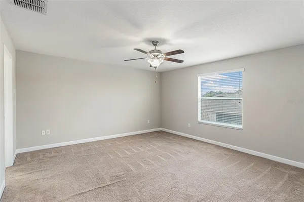 an empty room with windows and fan