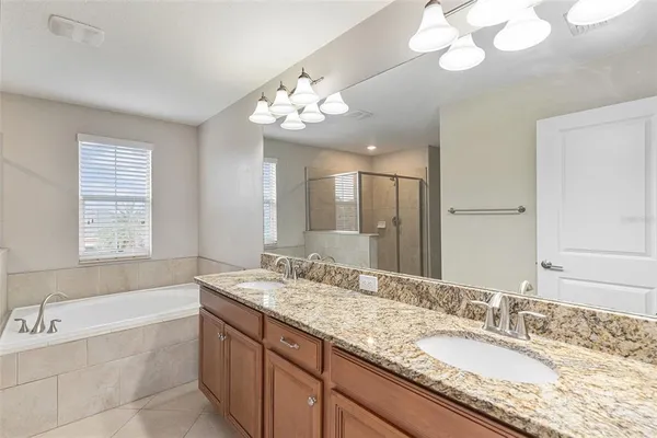 a bathroom with a granite countertop bathtub a sink and a large mirror