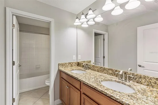 a bathroom with a granite countertop sink a toilet and a bathtub