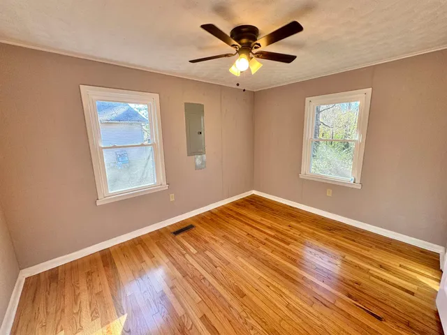 a view of an empty room with wooden floor and a window