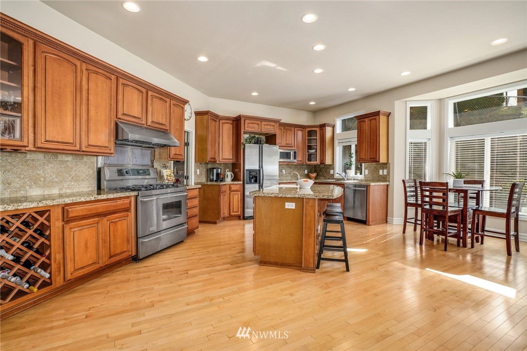 4113 Northeast 27th Place Renton, WA 98059 - Photo 11 of 27 a kitchen with stainless steel appliances granite countertop a stove top oven a sink a dining table and chairs