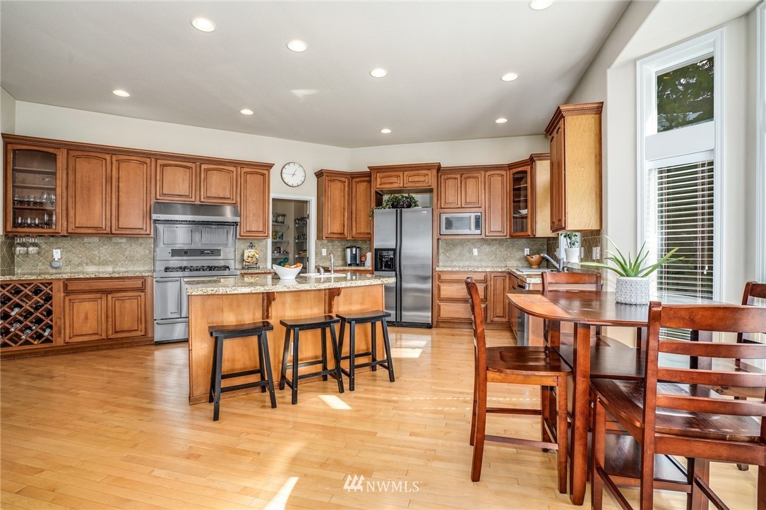 4113 Northeast 27th Place Renton, WA 98059 - Photo 12 of 27 a kitchen with stainless steel appliances kitchen island granite countertop a dining table chairs and granite counter tops