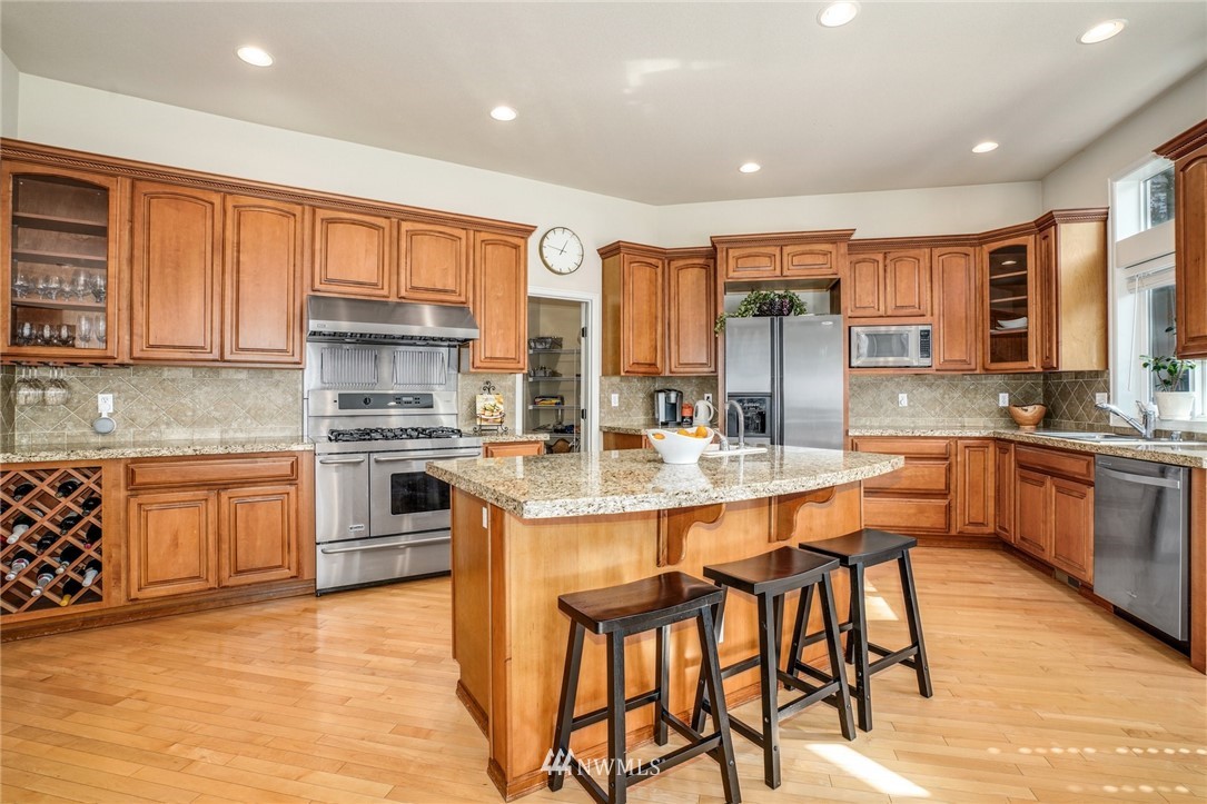 4113 Northeast 27th Place Renton, WA 98059 - Photo 13 of 27 a large kitchen with stainless steel appliances granite countertop a stove a sink dishwasher and a refrigerator with wooden cabinets