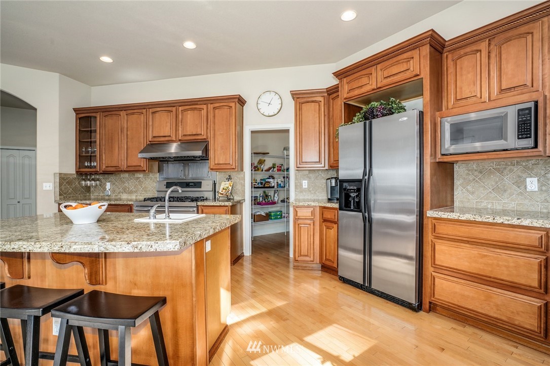 4113 Northeast 27th Place Renton, WA 98059 - Photo 10 of 27 a kitchen with stainless steel appliances granite countertop a refrigerator a stove and a sink with granite countertops
