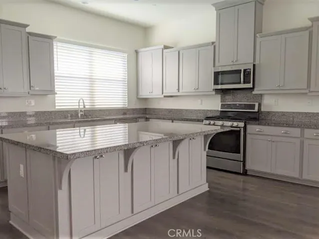 a kitchen with stainless steel appliances granite countertop white cabinets a sink and a stove
