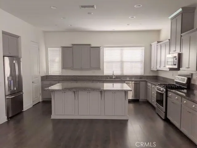 a kitchen with granite countertop a stove a sink and a refrigerator