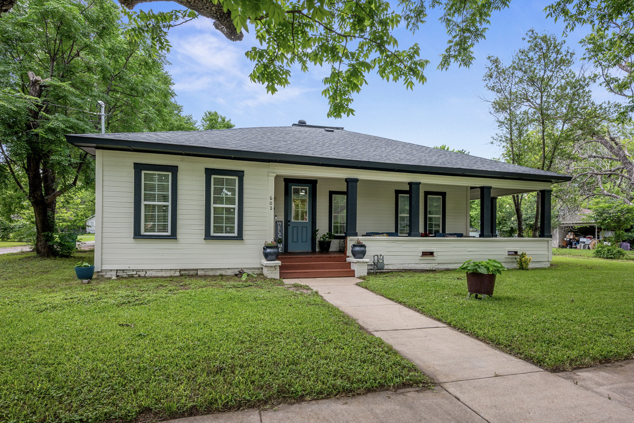 602 East 6th Street Cameron, TX 76520 - Photo 3 of 40 Single-story property featuring a covered front porch with dark pillars, a blue front door, and white siding with dark trim