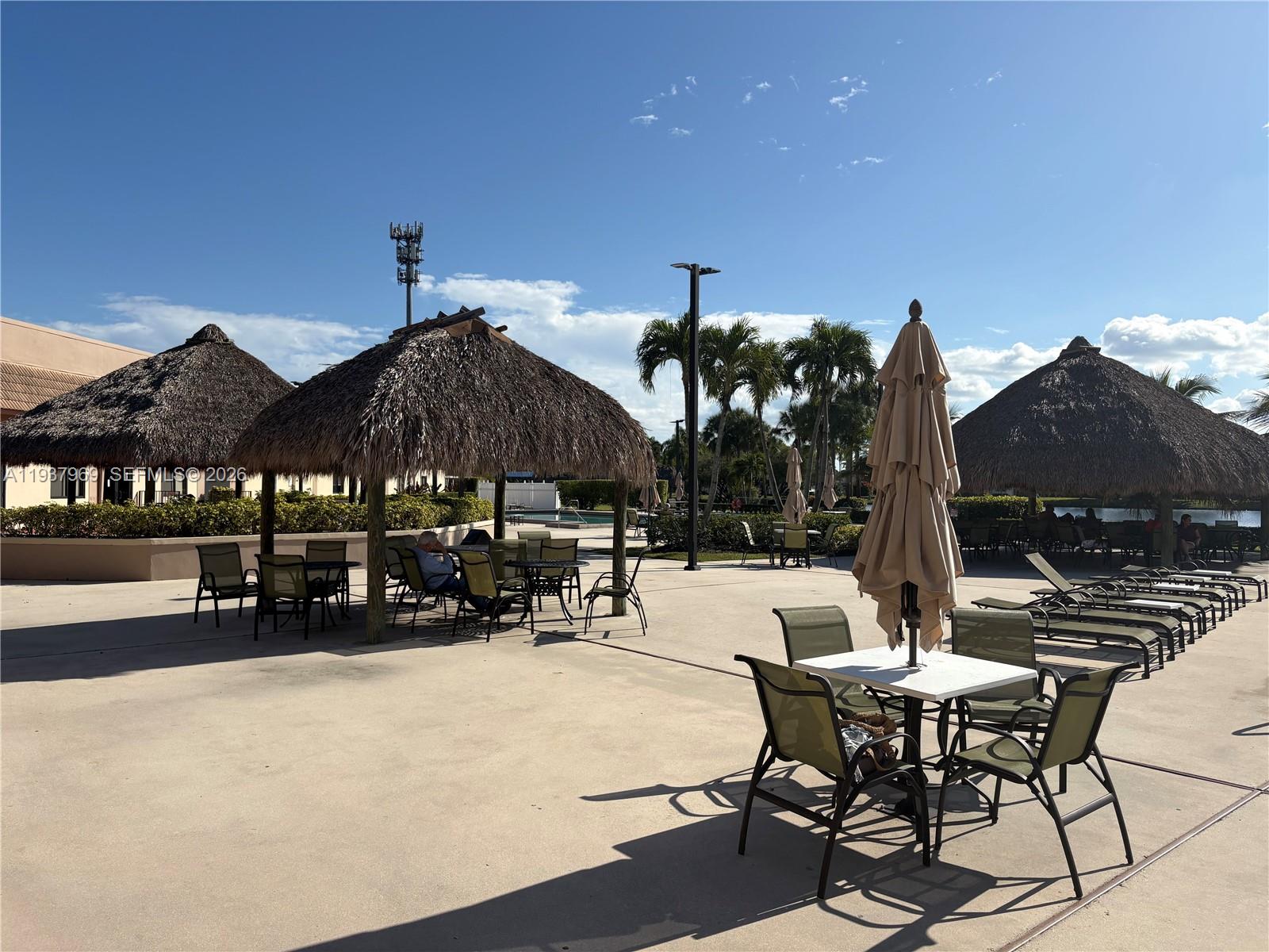 117 Danielle Court Weston, FL 33326 - Photo 38 of 43 a view of a patio with a table and chairs under an umbrella with a fire pit and a barbeque grill