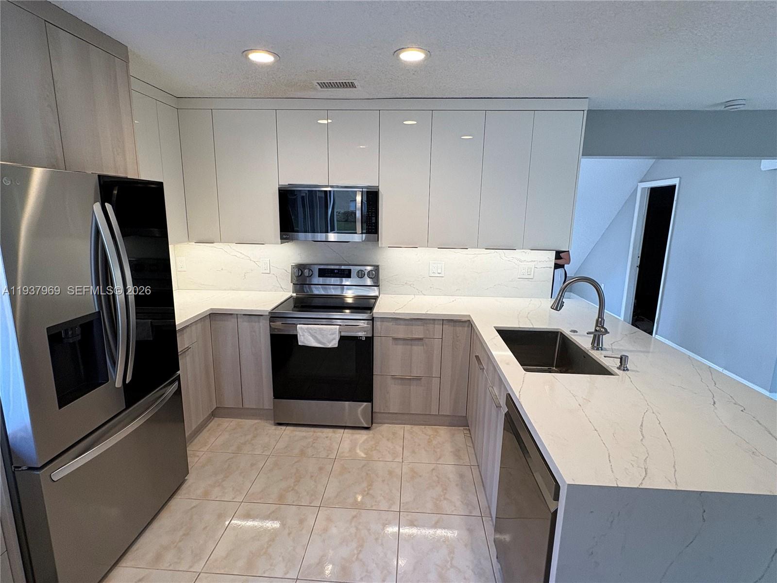 117 Danielle Court Weston, FL 33326 - Photo 8 of 43 a kitchen with a sink a stove a microwave and refrigerator