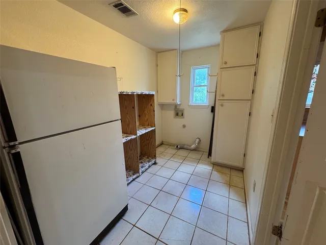 a view of a refrigerator in kitchen and an empty room in wooden floor