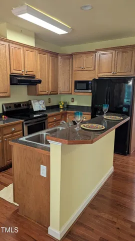 a kitchen with granite countertop a sink a stove top oven and cabinetry