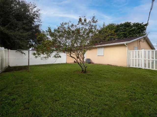 a view of a backyard with plants and large trees