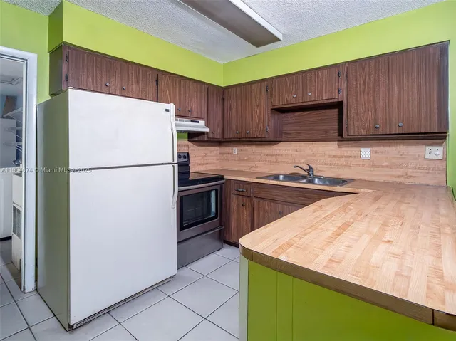 a kitchen with a sink a refrigerator and a stove top oven