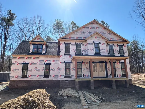 a view of a white house with large windows and a small yard with wooden fence