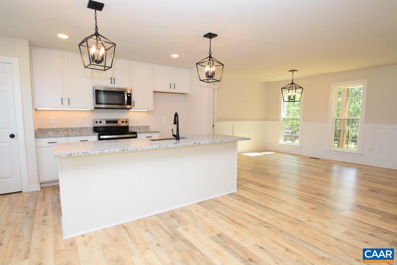 11675 Jack Jouett Road West Zion Crossroads, VA 22942 - Photo 6 of 32 a large kitchen with stainless steel appliances granite countertop a sink a microwave oven a stove and white cabinets with wooden floor