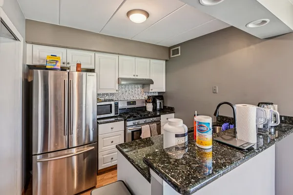 a kitchen with stainless steel appliances kitchen island granite countertop a refrigerator and microwave