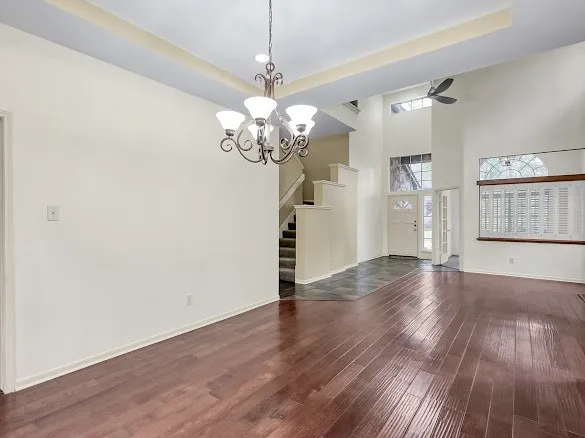 an empty room with wooden floor and a ceiling fan