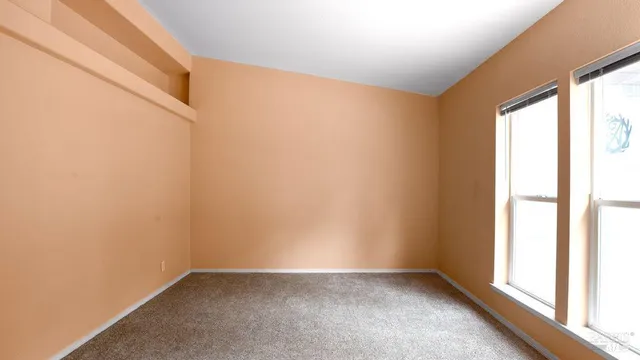a view of an empty room with window and wooden floor