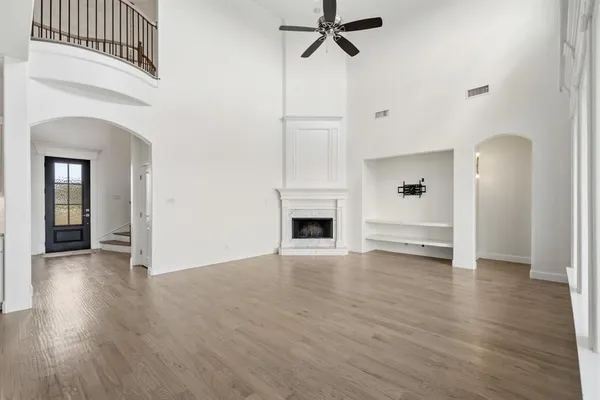 an empty room with wooden floor a ceiling fan and windows