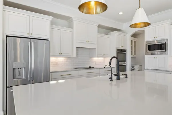 a kitchen with stainless steel appliances a stove a refrigerator a oven a sink a table and chairs