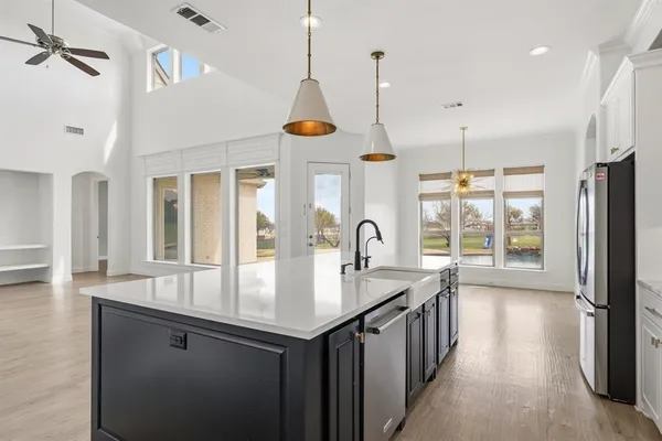 a kitchen with stainless steel appliances granite countertop a sink a center island and a wooden floor