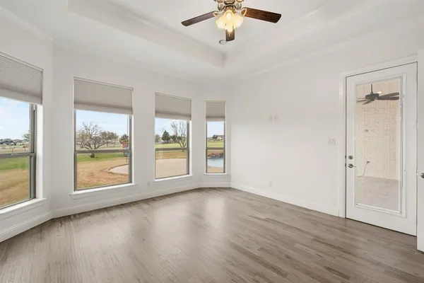 a view of an empty room with a window and wooden floor