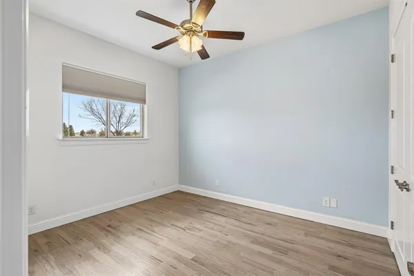 an empty room with wooden floor fan and windows